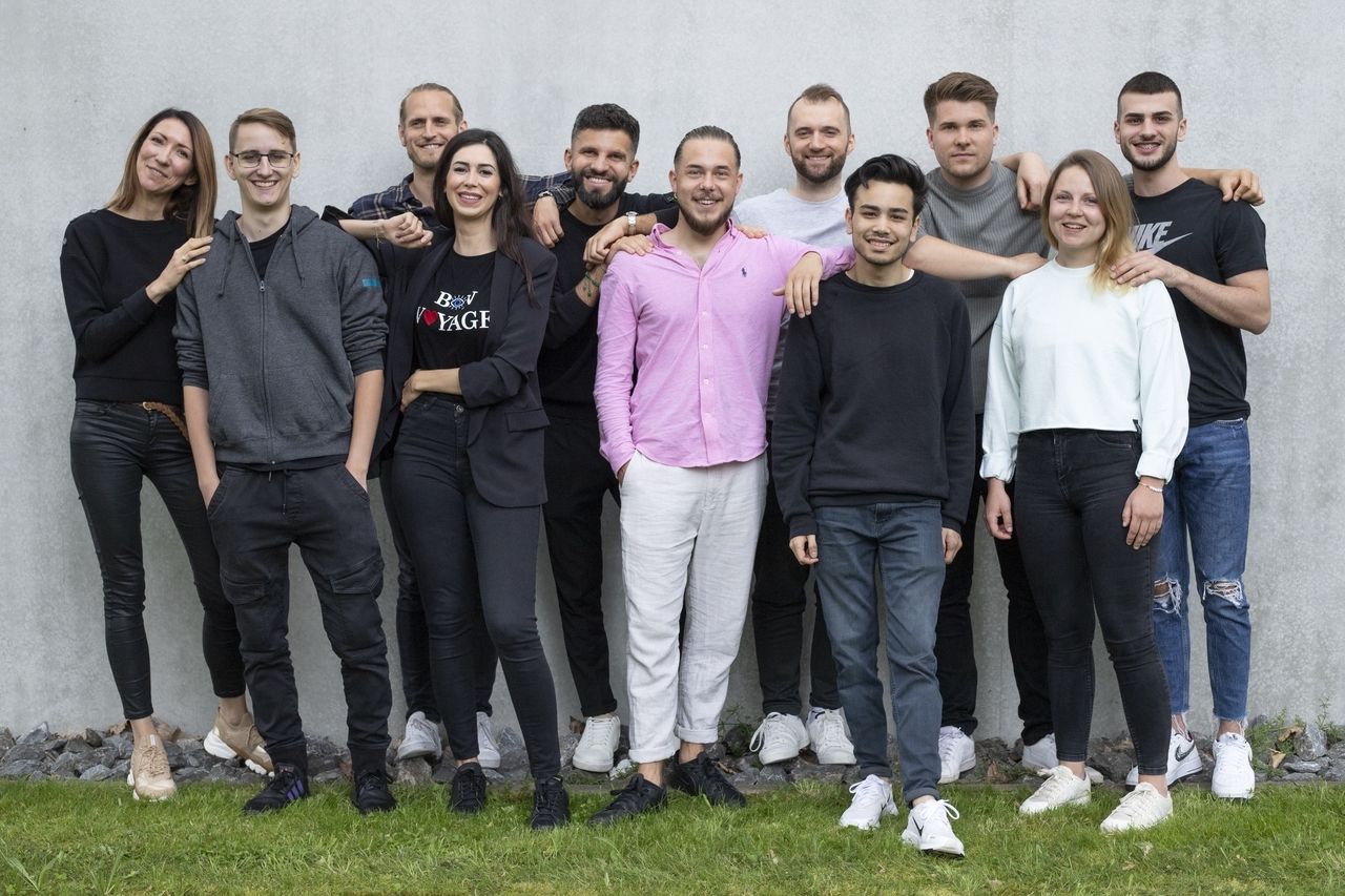 L'équipe de Crovillas sourit et pose pour une photo de groupe devant un mur gris.