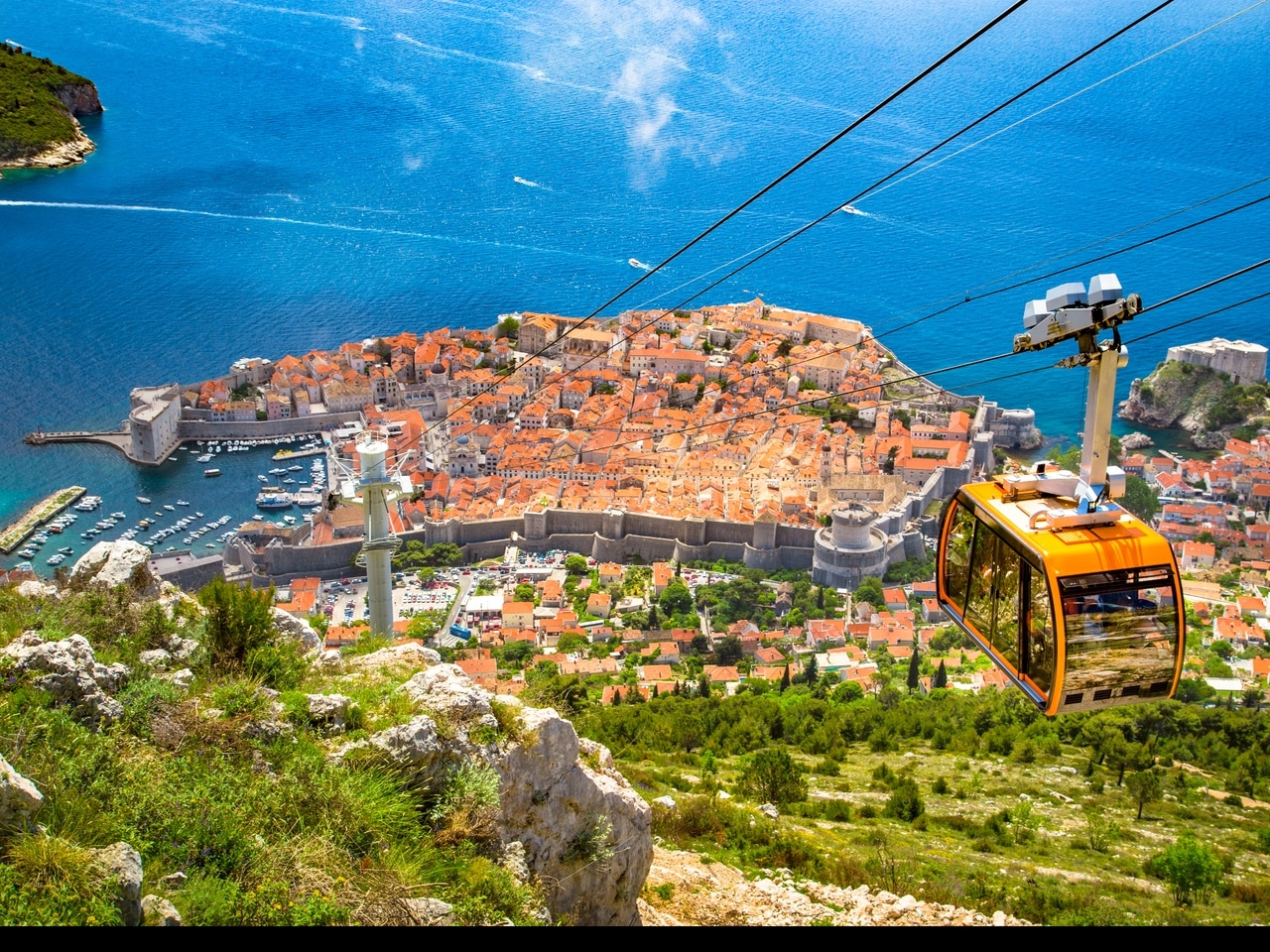 Andlöst vacker utsikt över Dubrovniks gamla stad i Kroatien från en linbana. De röda taken, de massiva stadsmurarna och det klara, blå vattnet i Adriatiska havet gör denna historiska stad till ett populärt turistmål.