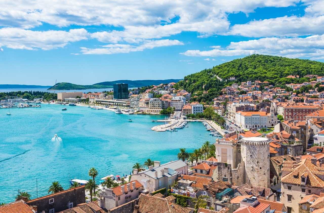 Panoramablik over kystbyen Split i Kroatien med dens historiske bykerne, den maleriske havn og de omkringliggende grønne bakker. Det klare, blå Adriaterhav og den charmerende arkitektur gør Split til et populært rejsemål.