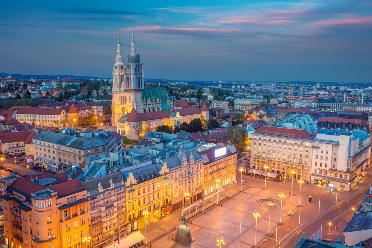 Kveldsutsikt over Ban-Jelačić-plassen og katedralen i Zagreb i Kroatia. De opplyste bygningene og historiske landemerkene gjenspeiler byens kulturelle og arkitektoniske mangfold.