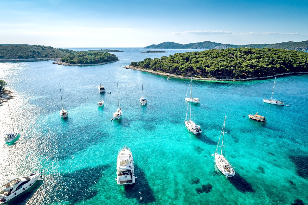 Sailboats and yachts in a picturesque bay near Hvar, Croatia, with turquoise water and wooded islands in the background